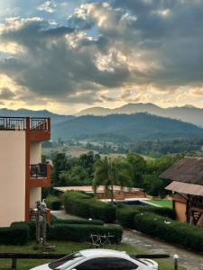 a car parked outside of a building with mountains in the background at Paihappyvillage in Pai