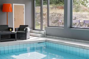 a room with a swimming pool with a chair and a table at Scandic Södertälje in Södertälje