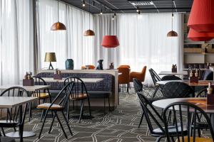 a restaurant with tables and chairs and windows at Scandic Södertälje in Södertälje