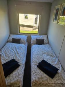 two beds in a small room with a window at Westfield 75 in Skipsea