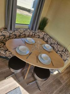 a wooden table with plates and glasses on it at Westfield 75 in Skipsea +9 photos