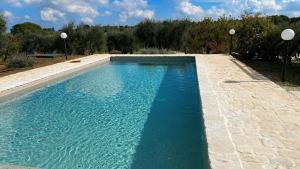 a swimming pool with blue water in a yard at Trullo al borgo in Cisternino