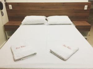 a bed with white sheets and white towels on it at Hotel Hallas in Betim +25 photos