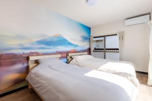 two beds in a bedroom with a painting on the wall at トキテラス五条 in Dazaifu +22 photos