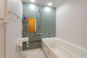 a bathroom with a tub and a sink and a shower at トキテラス五条 in Dazaifu