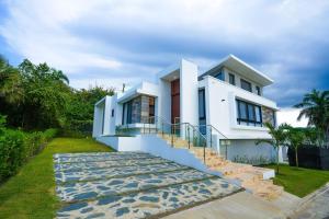 a white house with stairs in front of it at Modern Villa with a 15m Lap Pool, Cabarete in Cabarete
