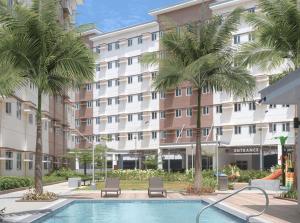 a hotel with a swimming pool and palm trees at Deck&Dwell in Trece Martires
