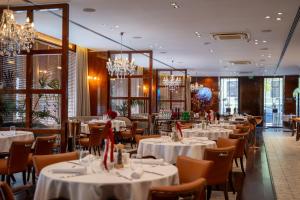 a restaurant with white tables and chairs and chandeliers at Hotel Royal Plovdiv in Plovdiv