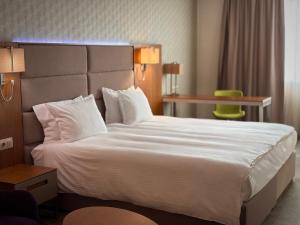 a hotel room with a large bed with white sheets and pillows at Hotel Golden Tulip Varna in Varna City
