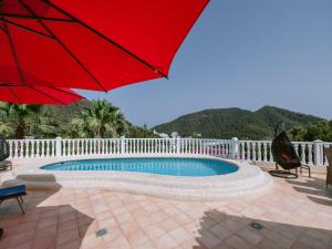 a red umbrella sitting next to a swimming pool at Villa in Cala Llonga near Beach & Ferry Port in Cala Llonga