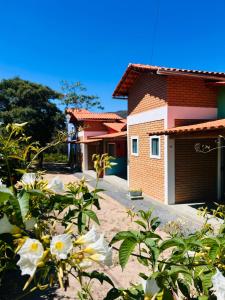 a house with a garage and flowers in front of it at Flor e Luz Chalés in Vale do Capao