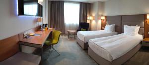 a hotel room with two beds and a desk at Hotel Golden Tulip Varna in Varna City