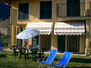 a table and chairs with an umbrella in front of a house at Appartamenti Maria Grazia in Dongo