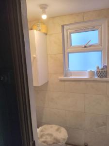 a bathroom with a toilet and a window at Honor in London