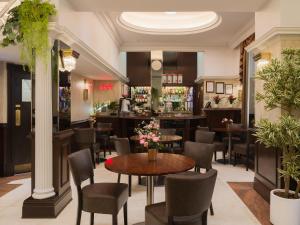 a restaurant with tables and chairs and a bar at Royal Eagle Hotel in London