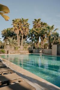 a swimming pool with palm trees in the background at Toison D'or in Saint-Tropez