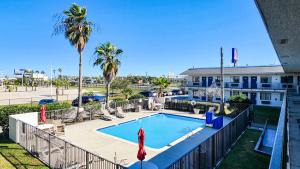 a swimming pool with palm trees and a building at Studio 6 Galveston TX in Galveston