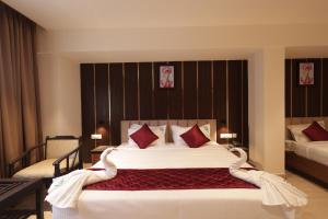 a bedroom with a large white bed with red pillows at KG Residency Inn in Thanjāvūr