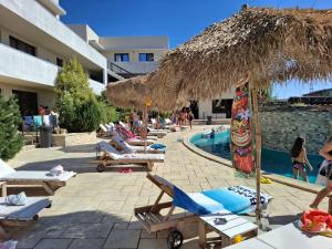 a resort with a pool with lounge chairs and a straw umbrella at Complex Casa Ani in Eforie Nord
