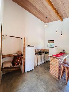 a kitchen with a white refrigerator and a counter at Flor e Luz Chalés in Vale do Capao