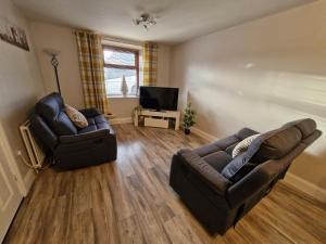 a living room with two couches and a television at Kellys Place Derry City Centre in Derry Londonderry