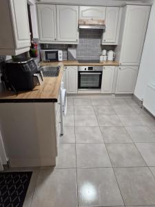a kitchen with white cabinets and a tile floor at Kellys Place Derry City Centre in Derry Londonderry