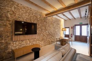 a living room with a couch and a tv on a stone wall at Mon Suites San Pedro in Valencia