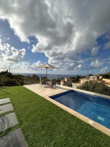 a swimming pool with an umbrella and some grass at Casa del jazmin Kfarabida in Kafr ‘Ubaydā +8 photos