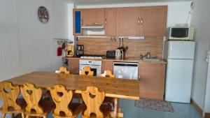 a kitchen with a wooden table and a refrigerator at Le Repaire du Loup blanc in Prémanon