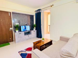 a living room with a couch and a tv at AeroNest Homes - 1BHK & 2BHK Quiet & Comfortable Near Airport 7km in Muthugadahalli