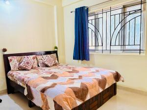 a bedroom with a bed with a blue curtain and a window at AeroNest Homes - 1BHK & 2BHK Quiet & Comfortable Near Airport 7km in Muthugadahalli