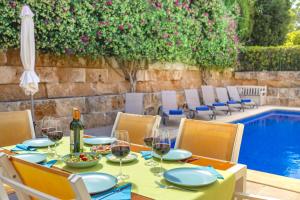 a table with glasses of wine and a meal next to a pool at Villa Synera in Alcudia +28 photos