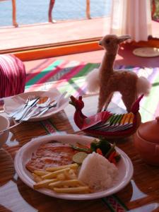 a table with a plate of meat and french fries at TiticacaIntiLodge in Puno +9 photos