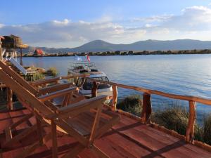 a dock with two chairs and a boat on the water at TiticacaIntiLodge in Puno