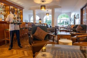 a man standing at a bar holding a bottle of wine at Mount Elgon Hotel & Spa in Mbale