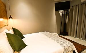 a bedroom with a white bed with green pillows at The Roaming Goat Guesthouse in Toekoms
