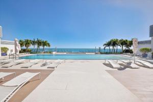 a swimming pool with lounge chairs and the ocean at MonteCarlo Miami Beach in Miami Beach