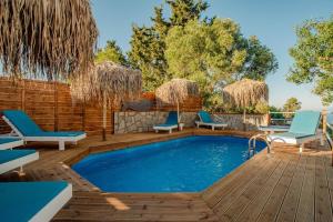a swimming pool with chairs and a wooden deck with a swimming poolvisor at Villa Kalimoukos in Corfu