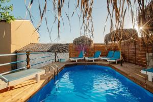 a swimming pool with blue chairs on a deck at Villa Kalimoukos in Corfu