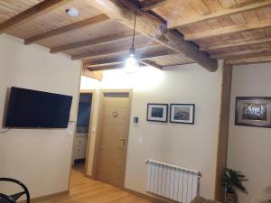 a living room with wooden ceilings and a flat screen tv at A casa do lajueiro in Arzúa