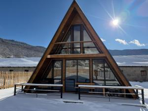 a triangular house with two benches in the snow at Mestia Inn Chalet in Mestia