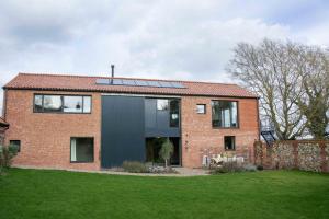 a brick house with solar panels on top of it at The Barn at Manor Farm in Great Glemham