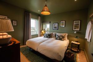 a green bedroom with a bed with pillows at The Barn at Manor Farm in Great Glemham