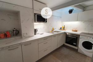a kitchen with white cabinets and a washer and dryer at Nicolaï Arles centre in Arles