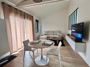a living room with a table and chairs and a television at Un toit pour 2 in Le May-sur-Èvre