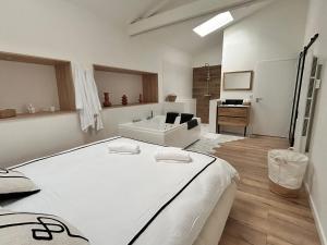 a white bedroom with a bed and a bathroom at Un toit pour 2 in Le May-sur-Èvre