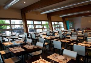 a dining room with tables and chairs and windows at Victoria Terme Hotel in Tivoli Terme