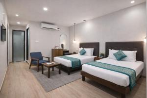 ein Hotelzimmer mit zwei Betten und einem Stuhl in der Unterkunft Hotel Comentom Vrindavan in Vrindāvan