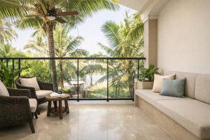 ein Wohnzimmer mit Sofa und Stühlen und Palmen in der Unterkunft Hotel Comentom Vrindavan in Vrindāvan