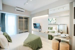 a white bedroom with a bed and a mirror at Yoonah at Benson Pakuwon Mall in Lontar